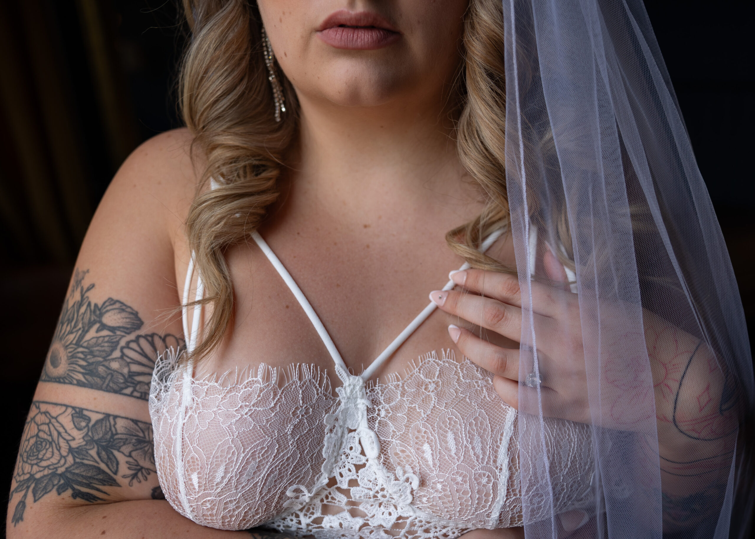 Details of a bride's hand on her chest with engagement ring in white lace bra after finding bridal shops in dc