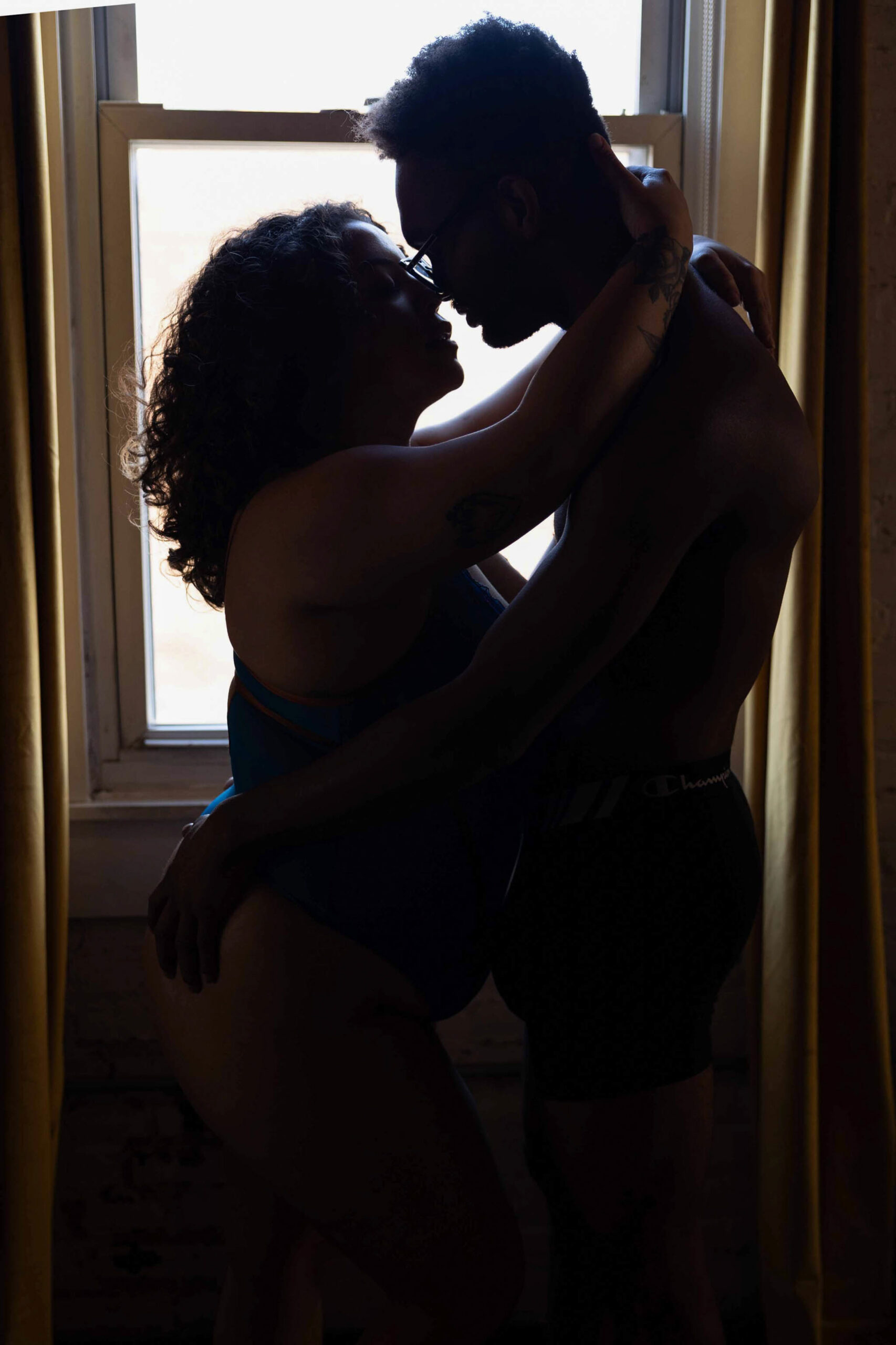 A happy couple embrace for a kiss in a window while staying at luxury hotels in northern virginia