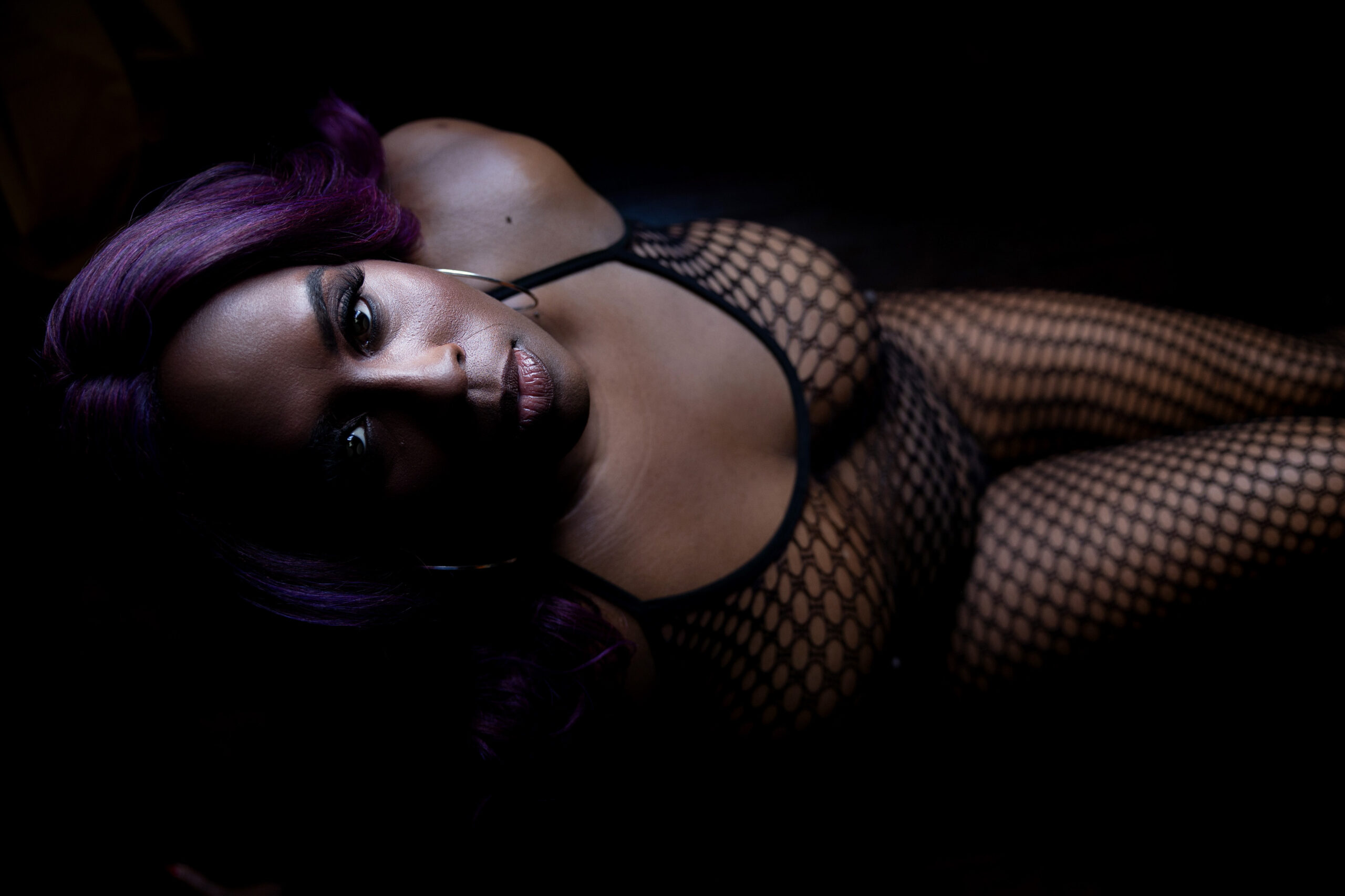 A look down at a woman looking up in a black mesh bodysuit after finding personal trainers in dc