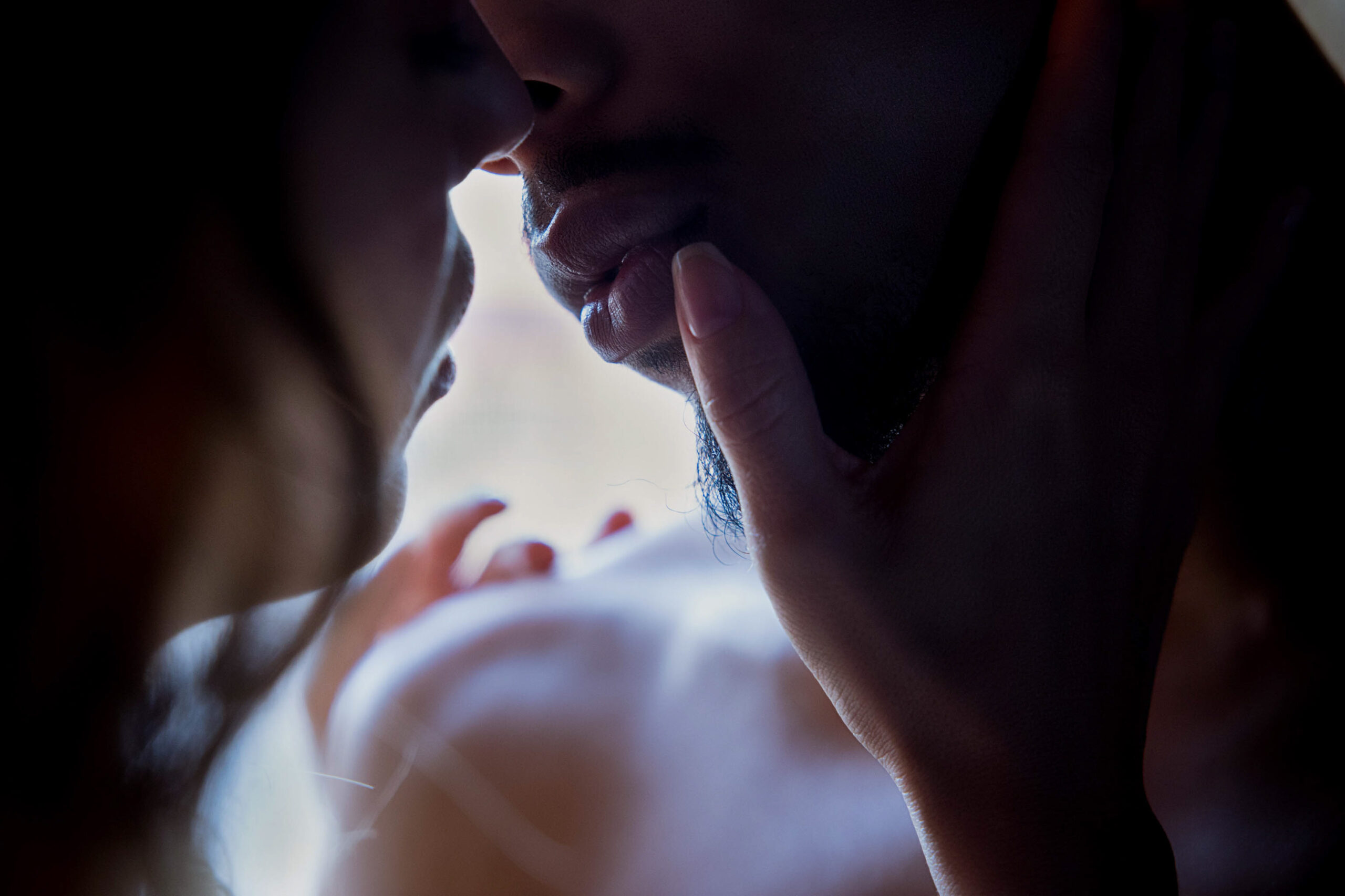 Details of a couple leaning in for a kiss in a window after exploring bridal shops in maryland
