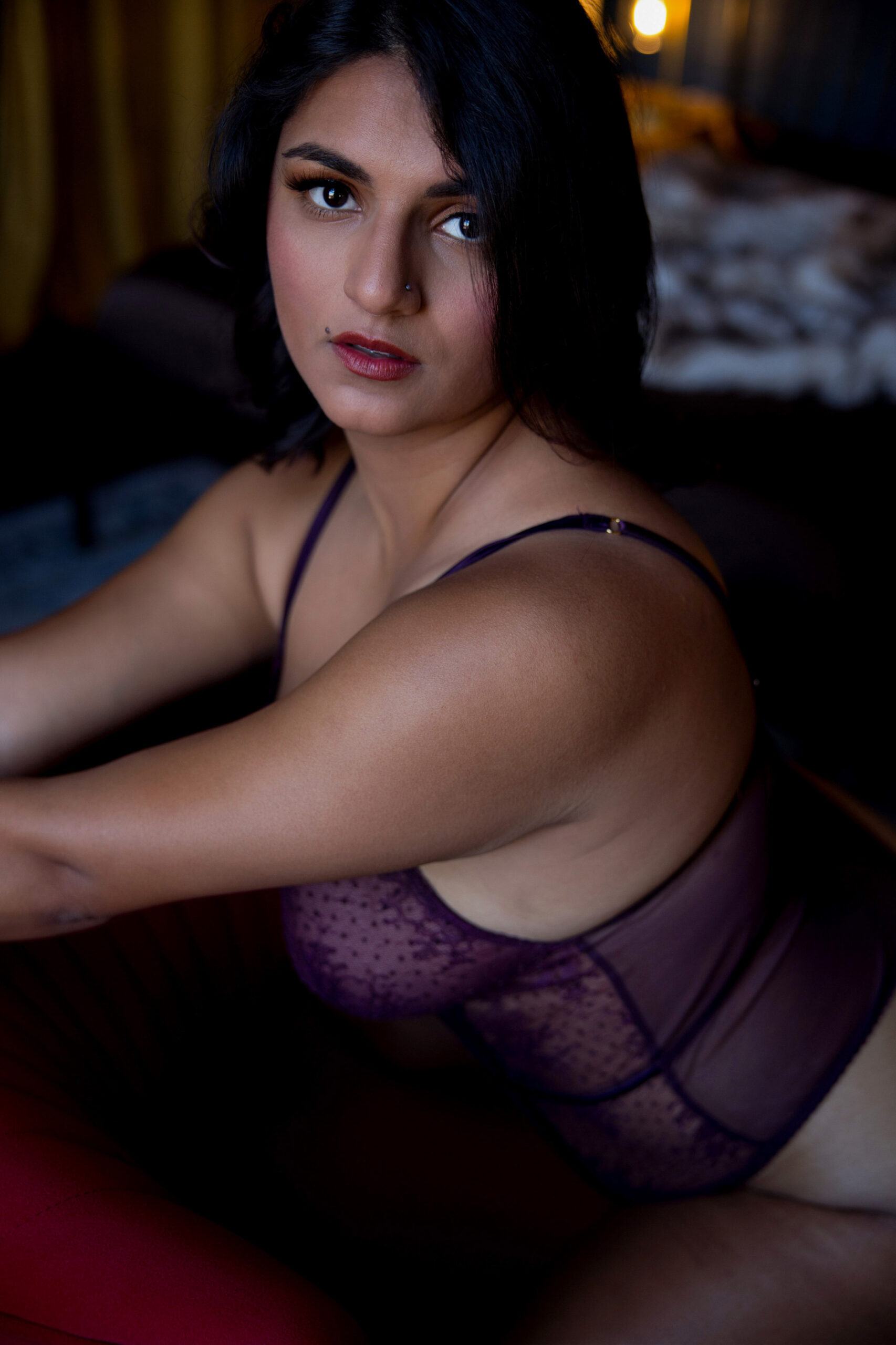 A woman kneels in a studio with short dark hair and purple lingerie after meeting a personal trainers in maryland