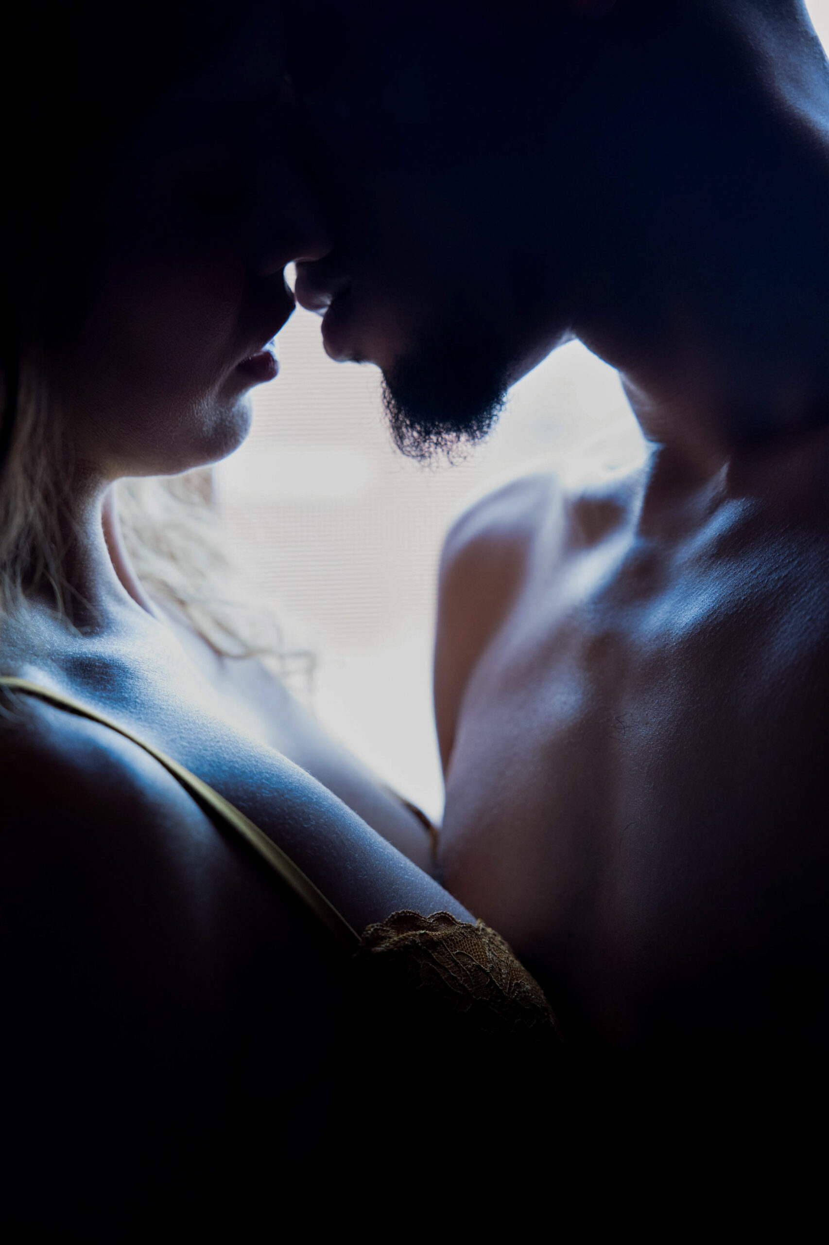 Details of a couple leaning in for a kiss in silhouette in a window during their romantic getaways in northern virginia