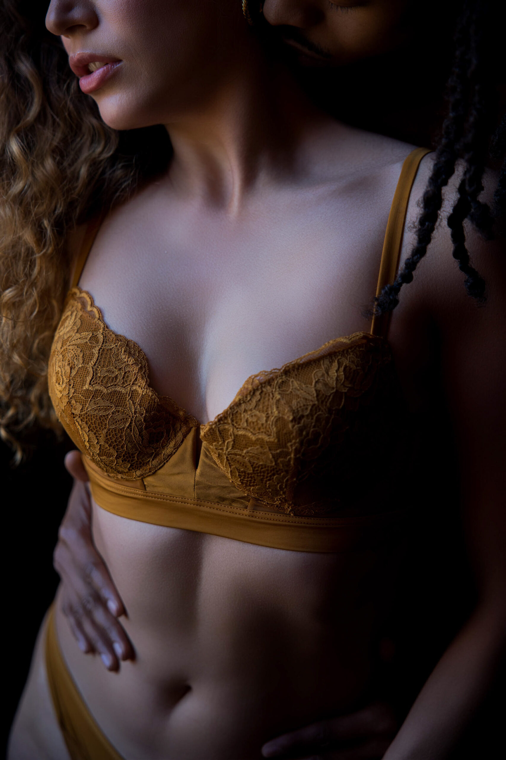 A closeup of a woman with her boyfriend's hand on her stomach in a gold bra after visiting romantic restaurants in maryland